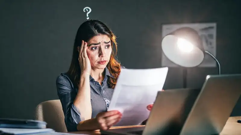 Una mujer confusa consulta documentos financieros